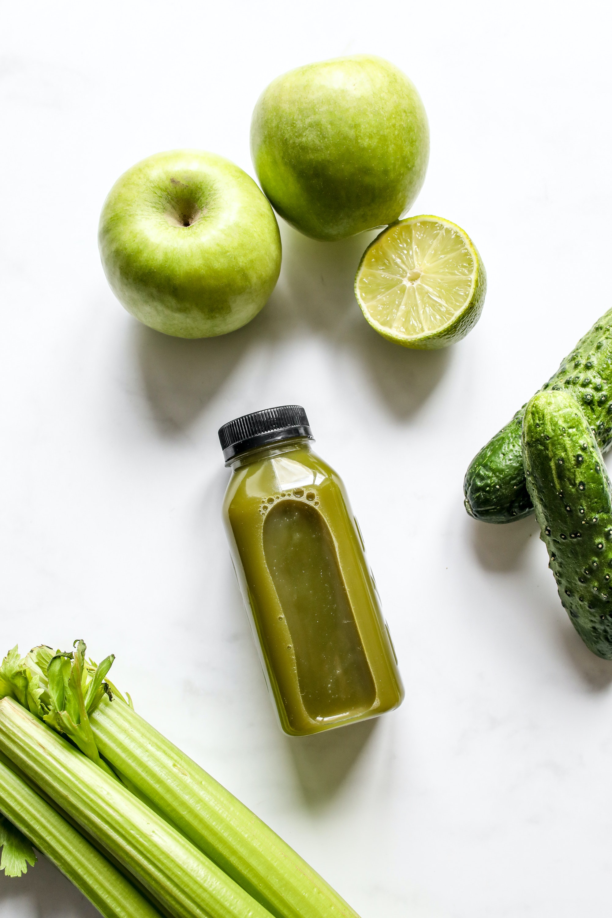 Smoothie with apple, cucumber, lime and celery besides it.